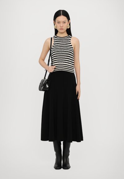 Svart-og-hvitt stripet strikket tank topp paired med en flytende svart maxiskjørt og knelengde svarte støvler. Liten svart crossover-veske.
