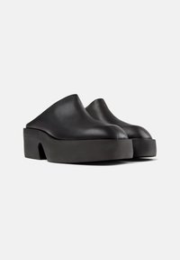 Saboti din piele neagră cu vârf rotund, spate jos și platformă groasă, texturată. Finisaj neted și design minimalist.