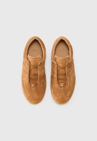 Sneakers din suede maro, cu vârf rotund, design cu șireturi, cusături contrastante și un mic detaliu de logo pe față. Interior neted.