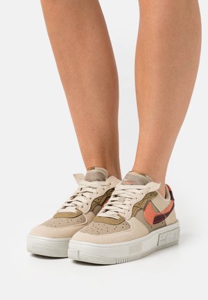 Beige mockasneakers med orangea och mörkröda detaljer, texturerad tå, platta snören och vadderad plös. Tjock vit gummisula.