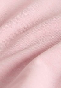 Tissu tricoté rose doux avec une texture de tissage visible et de légers plis créant des ombres subtiles.
