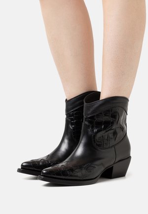 Schwarze Cowboy-Stiefel aus Leder mit leicht spitz zulaufender Spitze, strukturierten Akzenten im Krokodilmuster und niedrigem Blockabsatz.