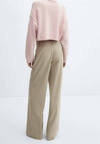 Helles rosa, kurz geschnittenes Sweatshirt mit gerippten Bündchen und Saum, kombiniert mit beigefarbenen, weit geschnittenen Hosen in taillierter Passform und mit Gesäßtaschen.