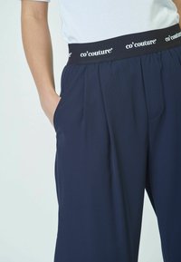 Jūrų laivyno elastingi juosmens kelnės su co’couture prekės ženklo ženklinimu, turinčios šonines kišenes ir lygų, tekstūruotą audinį. Atsipalaidavęs kirpimas ir pilno ilgio dizainas.