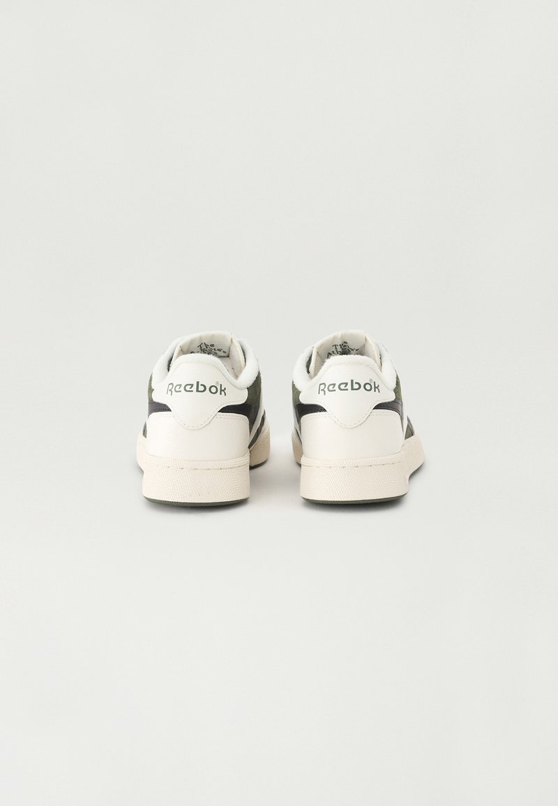 Baskets Reebok noir et blanc avec des matériaux en daim et cuir, col rembourré, logo au niveau du talon et semelle en caoutchouc blanc texturé.