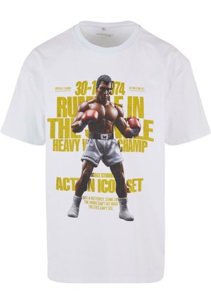 Biely bavlnený tričko s grafickým potlačou boxera v šortkách a červenými rukavicami. Text obsahuje "Rumble in the Jungle" a dátumy, v žltej farbe.