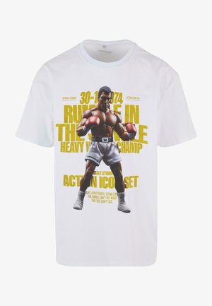 Biely bavlnený tričko s grafickým potlačou boxera v šortkách a červenými rukavicami. Text obsahuje "Rumble in the Jungle" a dátumy, v žltej farbe.