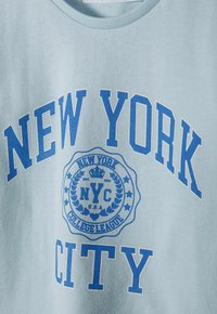 Svijetloplava dukserica s istaknutim plavim natpisom "NEW YORK CITY" i kružnim grbom s natpisom "NYC COLLEGE LEAGUE" te dizajnom lovorovog vijenca.