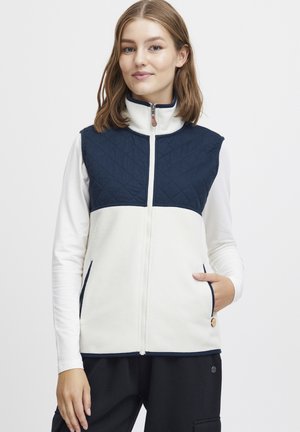 Fleecevest med en marineblå quilted overdel og lys creme underdel. Har en stående krave, frontlynlås og to sidelommer.