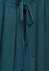 Gonna in tessuto teal con vita arricciata e chiusura a fiocco, morbida al tatto, dal design ampio e fluido con una leggera lucentezza.