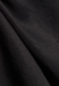 Schwarzer Stoff mit einer glatten Textur, der ein dezentes Webmuster aufweist. Der Stoff wirkt weich und flexibel.