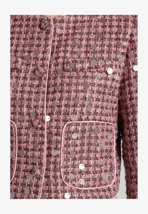 Roze tweed jasje met pailletten. Kenmerkt zich door ronde knopen, afgesneden randen en twee voorzakken. Textuur is geweven en gelaagd met decoratieve elementen.