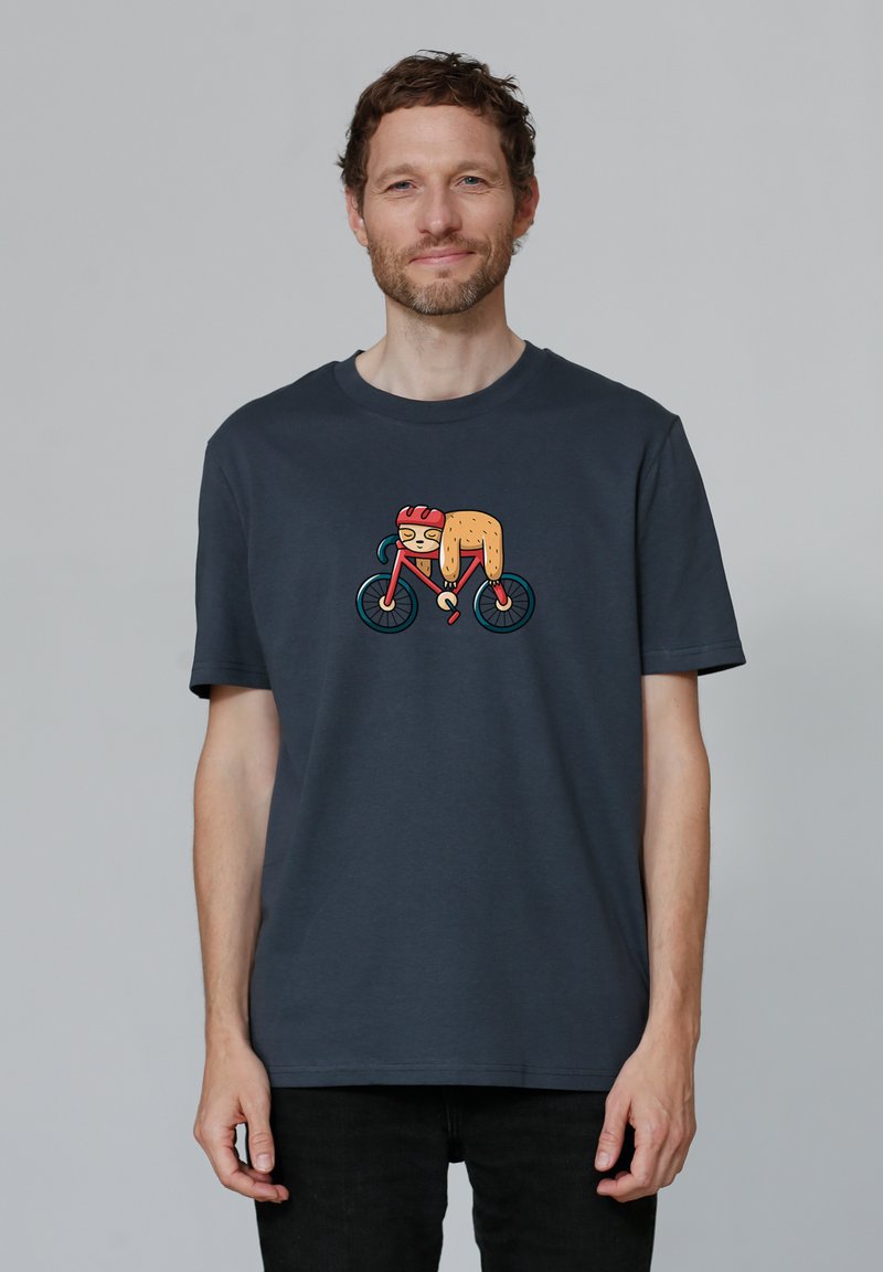 T-shirt en coton bleu marine à manches courtes, arborant un graphique coloré d'un paresseux sur un vélo, avec des accents vibrants et une texture douce.