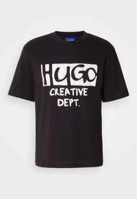 Black cotton t-shirt with white graphic text reading "HUGO" and "CREATIVE DEPT." in bold, playful fonts. Crew neck and short sleeves.