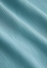 Tela azul claro con textura y finas líneas horizontales que crean sutiles ondulaciones, mostrando una superficie suave y lisa.