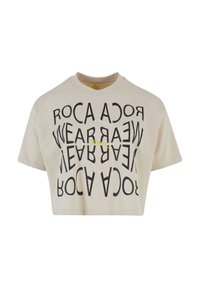 Cream cropped T-shirt with black graphic text in a circular pattern. Simple round neckline and short sleeves, made from soft cotton material.