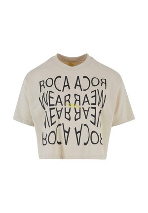 Kremowa krótka koszulka z czarnym napisem graficznym w okrągłym wzorze. Prosty okrągły dekolt i krótkie rękawy, wykonana z miękkiego bawełnianego materiału.