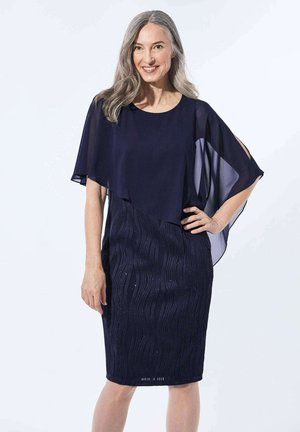 Marineblaues Kleid mit einer geschichteten, durchsichtigen Drapierung und strukturiertem Wellenmuster. Der Stoff hat einen dezenten Glanz und ist tailliert.