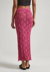 Gonna maxi in magenta con motivo a rete. L'orlo svasato e la vita elastica offrono una silhouette fluida. Indossata con sandali neri.