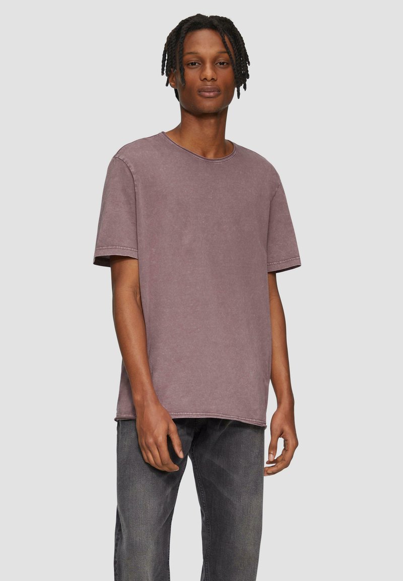 Korte mouwen, mauve katoenen t-shirt met een ronde hals, een comfortabele pasvorm en onafgewerkte zoomranden, gecombineerd met donkergrijze jeans.