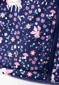 Tessuto navy con fiori rosa e gialli, funghi rossi, una fata con ali rosa e un unicorno bianco con criniera colorata vicino a una cerniera.