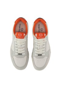 Baltas sneakers ar pelēki zamšādas akcentiem, oranžu iekšpusi, plakaniem šņorēm un logo birku. Perforācijas detaļas uz pirkstiem piešķir tekstūru.