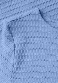 Blått texturerat tyg med ett rutmönster och upphöjda inslag. Materialet har en mjuk framtoning och en något texturerad känsla.