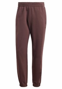 Pantaloni della tuta marroni con vita elasticizzata, gambe a sigaretta, tasche laterali e una texture liscia. Adatti per abbigliamento casual o sportivo.