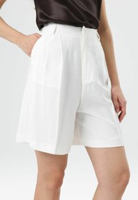 Witte geplooide shorts gemaakt van een lichtgewicht stof, met een hoge taille, zijzakken en een losse pasvorm voor comfort.