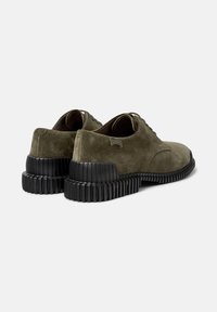 Scarpe in suede verde oliva con una suola in gomma nera segmentata unica, mostrano il retro e i lati.