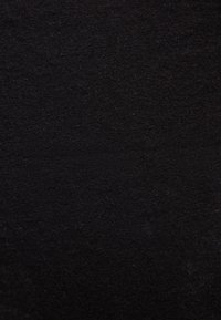 Κοντινό πλάνο μαύρου πλεκτού υφάσματος που δείχνει λεπτομερή υφή και κομψό μοτίβο ραφής.