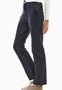 Jeans de mezclilla oscura con corte recto, alta cintura, cinco bolsillos y detalles de costura sutiles. Acabados con acentos de herrajes metálicos.