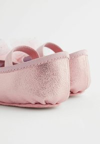 Pinke Ballettschuhe mit metallischem Finish, ausgestattet mit einer weichen, abgerundeten Ferse und elastischen Riemen. Strukturierte Oberfläche mit leichten Schimmerakzenten.