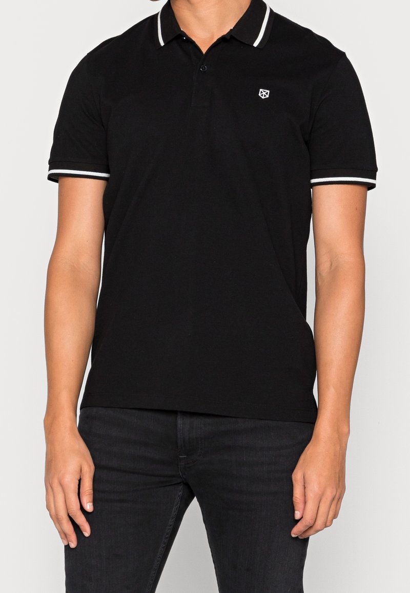 Schwarzes Polo-Shirt mit Kragen und weißen Streifenakzenten. Besitzt ein kleines Logo auf der Brust und hat kurze Ärmel, gefertigt aus strukturiertem Stoff.