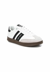 Sneakers bianche con strisce nere e dettagli in suede grigio. Suola in gomma, stringhe piatte e logo sulla linguetta. Design atletico classico.
