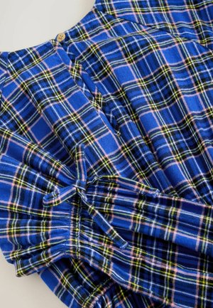 Mėlyna languota suknelė, kurios raštas yra tamsiai žalias, rožinis ir juodas, su surinktomis rankovėmis ir mygtuko detale apykaklėje.