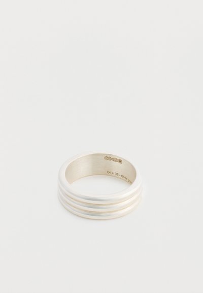 Bague en argent avec une finition lisse et polie, ornée de trois bandes en relief. Gravure intérieure visible. Forme ronde avec un intérieur mat.