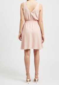 Różowa sukienka bez rękawów z dekoltem w kształcie litery V, elastycznym pasem i rozkloszowanym dołem. Wykonana z gładkiej tkaniny, sięga powyżej kolan.