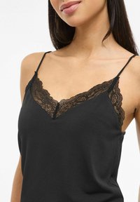 Czarna koszulka na ramiączkach z delikatną koronkową lamówką przy dekolcie i cienkimi, regulowanymi ramiączkami. Gładka faktura materiału i dekolt w serek.