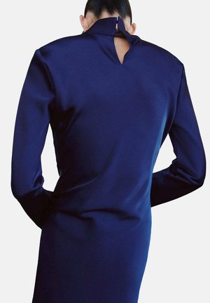Vestido de manga larga color azul marino, con cuello alto y un corte en forma de lágrima en la espalda, confeccionado en una tela suave y texturizada.