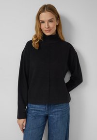 Schwarzer Rollkragenpullover mit lockerer Passform und überschnittenen Schultern. Hergestellt aus weichem Stoff, mit geripptem Ausschnitt und schlichten Linien.