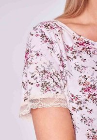 Kwiatowy top z kr�ótkim rękawem w jasnoróżowej tkaninie, z koronkowym wykończeniem na rękawach i delikatnym wzorem róż i liści.