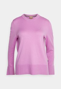 Maglione lungo a maniche lunghe di colore rosa, con scollatura rotonda, logo sottile sul petto e polsini svasati. Texture liscia e vestibilità comoda.