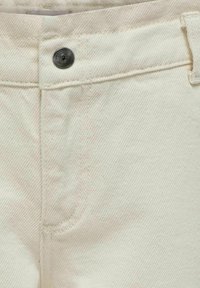 Pantalon en denim beige clair avec une surface texturée, featuring un bouton noir, des coutures surpiquées et des ouvertures de poches avant.