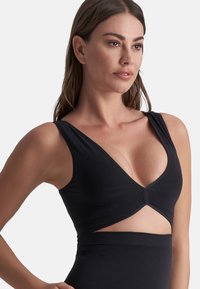 Zwarte sporttop met een diepe V-hals, uitsnijdingen bij de taille en brede schouderbanden, gemaakt van gladde, rekbare stof.