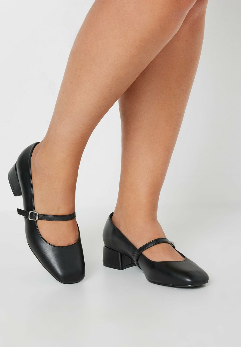 Svarta läder Mary Jane-skor med låg klack, böjd tå och en dekorativ rem med spänne över fotryggen.