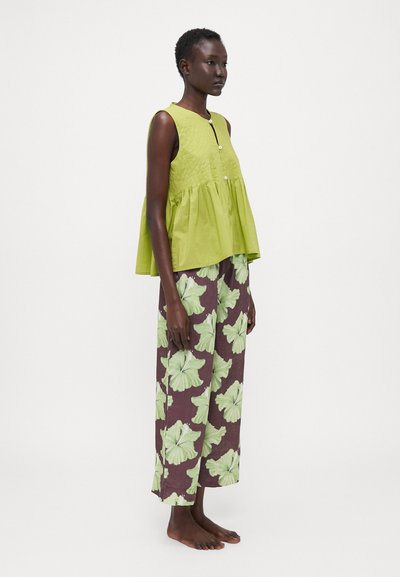 Lime green sleeveless blouse with button closure, paired with brown pants featuring large green floral patterns. Soft, lightweight fabric.