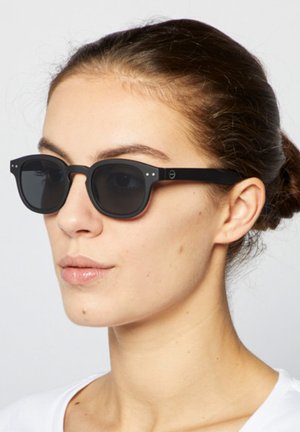 Czarne prostokątne okulary przeciwsłoneczne z ciemnymi soczewkami, z małymi srebrnymi akcentami na oprawce i matowym wykończeniem. Cienkie ramiona z detalem marki.