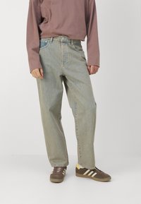 Lyseblå denimjeans med en avslappet passform, med høy midje, fem lommer og en falmet finish. Kombinert med brune og gule joggesko.