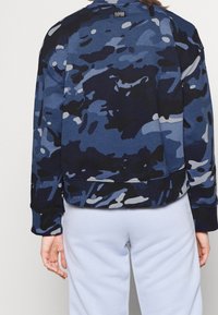 Marinblå camouflagesweatshirt med rundad halsringning och ribbade ärmslut. Tillverkad av mjukt tyg, med kontrasterande ljusblå detaljer.